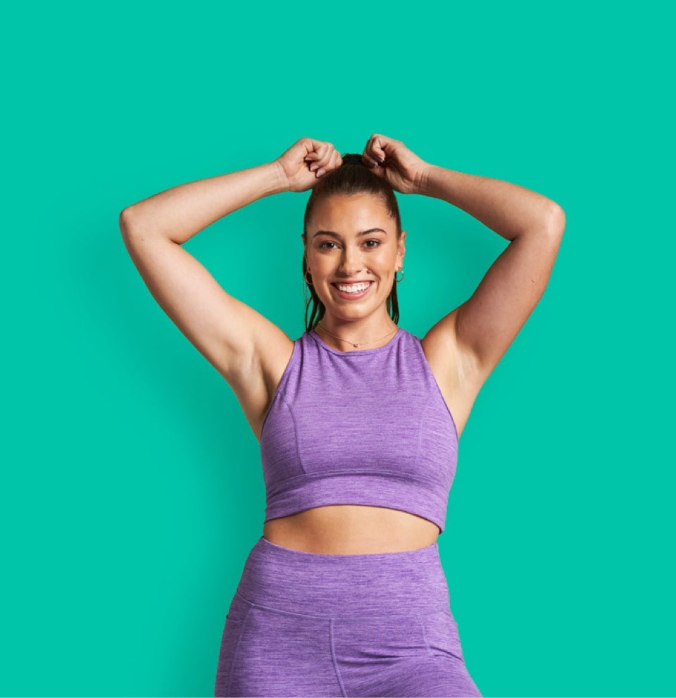 Smiling woman in workout clothes with her arms above her head